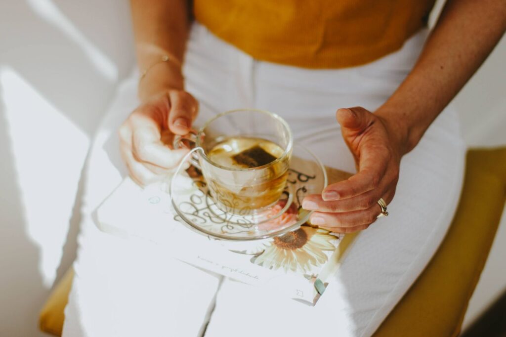 A serene scene of a person enjoying herbal tea while holding a book on a sunny day.
